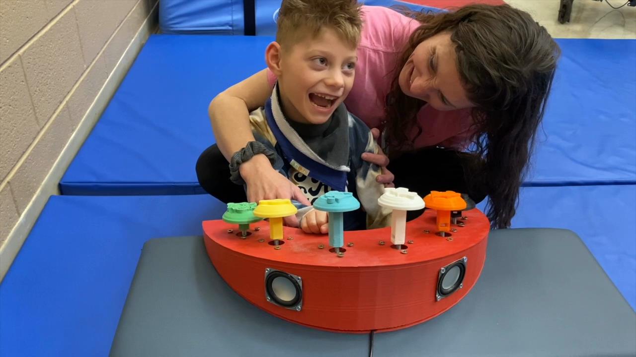 A child using a 3D printed audio sound toy with disney-themed toggles.