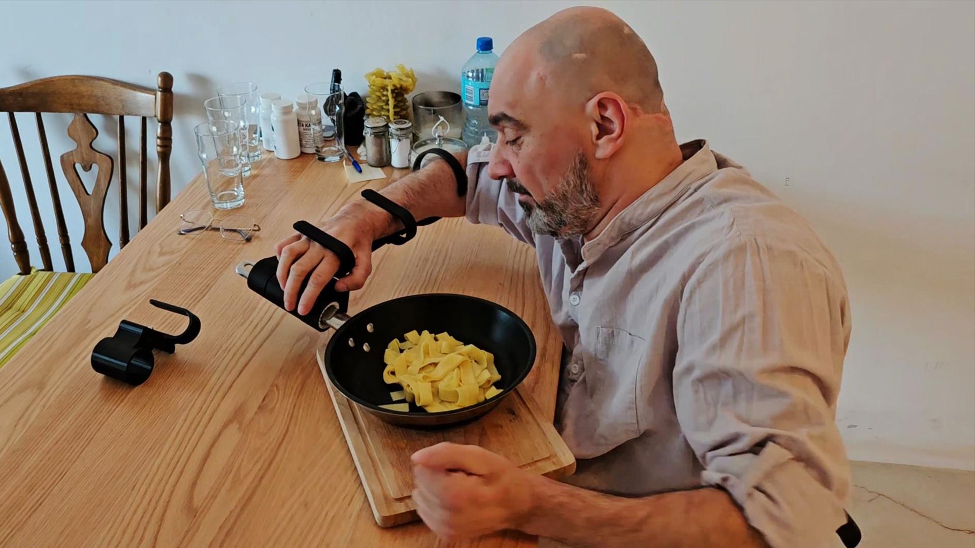 Person holding a pan with a 3D printed assistive gripping aid.